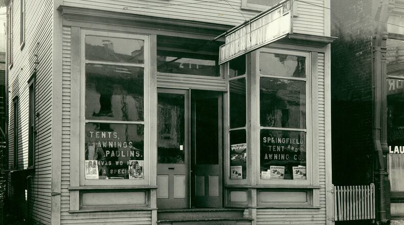 Around 1880, the Dial family came to Ohio from Illinois and settled in Dayton. The elder Dial, Absalom, worked as a salesman, and following is death in 1886, his young son, George Hooker Dial began work as an awning maker. By 1898, George struck out on his own, briefly working in Columbus before moving to Springfield to start the Springfield Tent and Awning Company, which was originally located on W. Main Street. George moved to Columbus in 1910 and continued in the tent and awning business, but the business he had started remained in Springfield. They made awnings, tents, flags, and camp furniture, often showcasing the awning work they did for many residences around town. They are shown here in September 1929 at 211 E. Main Street. PHOTO COURTESY OF THE CLARK COUNTY HISTORICAL SOCIETY
