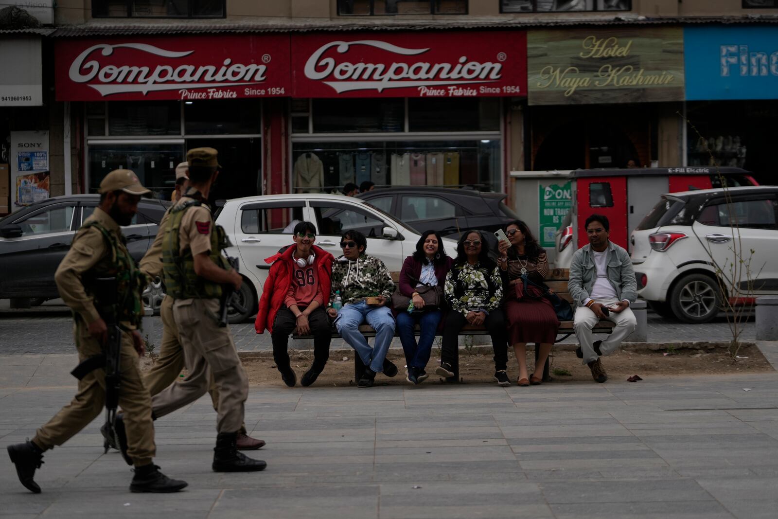 Indian tourists rests on a bench as policemen guard near a clock tower at city centre in Srinagar, Indian controlled Kashmir,Tuesday, April. 22, 2025. (AP Photo/Mukhtar Khan)