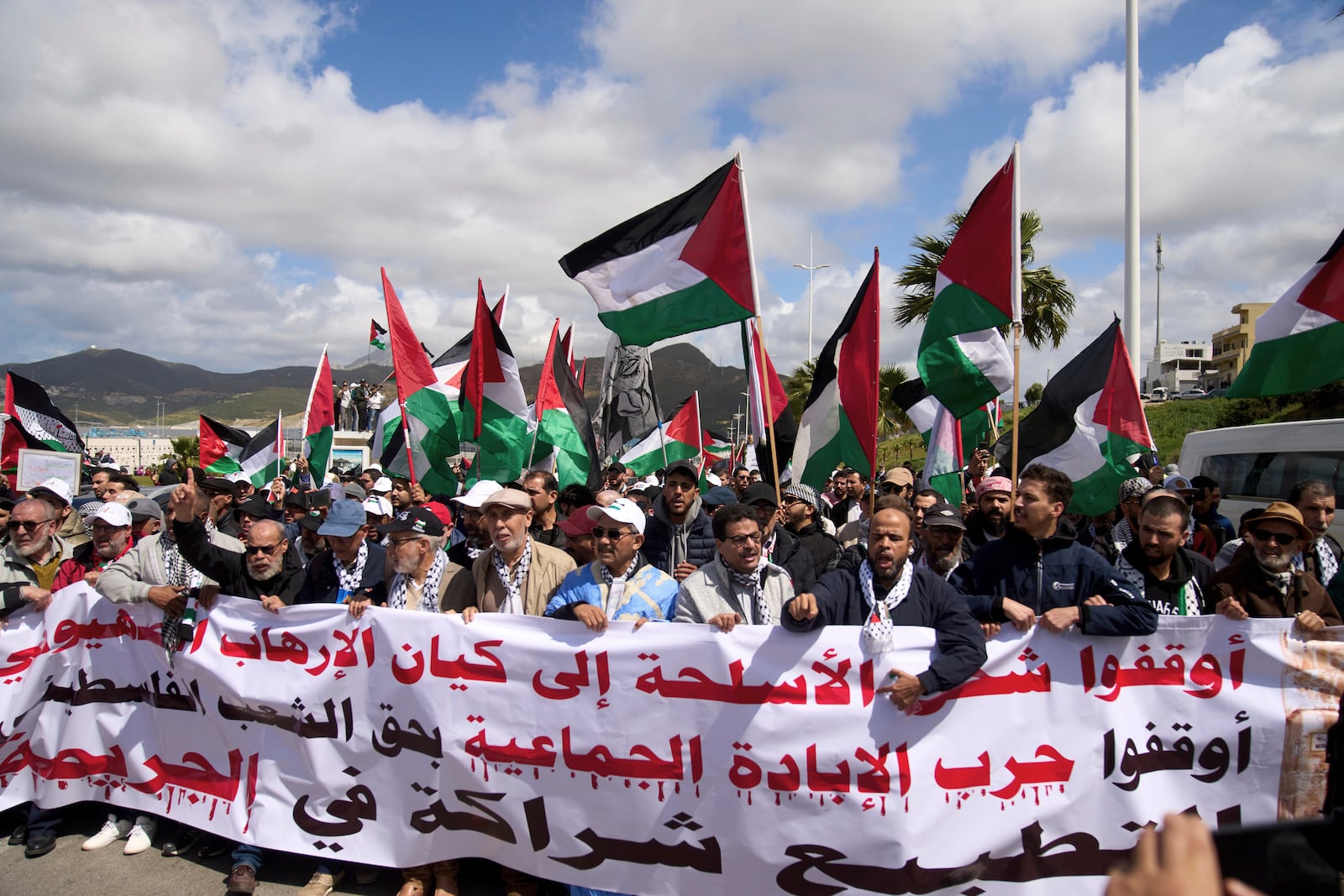 Moroccans protest the docking of a Maersk cargo ship carrying airplane parts they suspect are headed to Israel, outside Tangier Med Port, Sunday, April 20, 2025. Banner in Arabic reads "Stop shipping weapons to the terrorist Zionist entity." (AP Photo/Mosa'ab Elshamy)