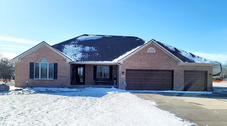 The front of the contemporary brick ranch has a covered porch and an extended concrete driveway with a three-car attached garage. CONTRIBUTED