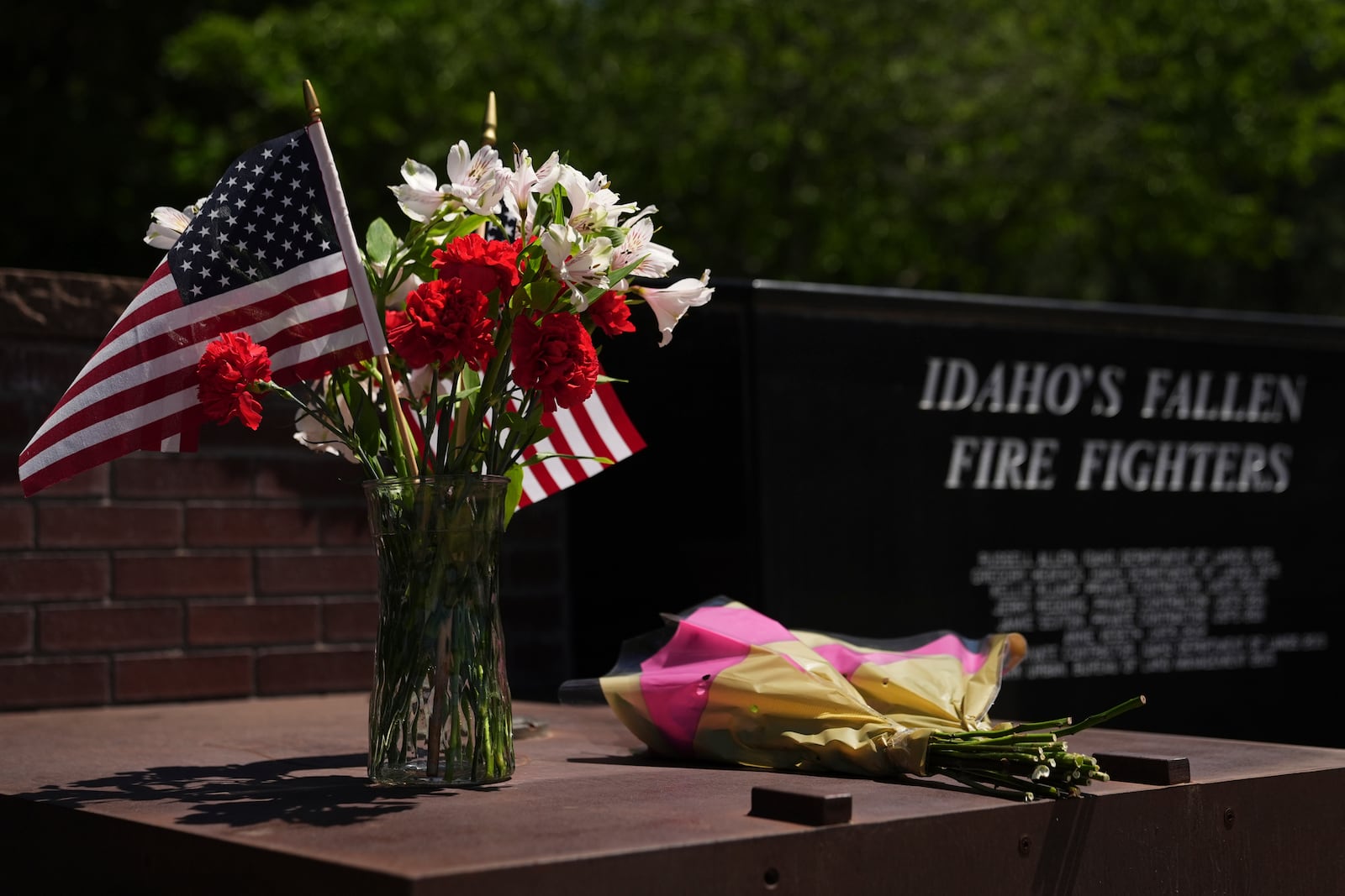 Flowers are seen at the Fallen Heroes Plaza at Cherry Hill Park near the scene the day after a shooter ambushed and killed firefighters responding to a wildfire at Canfield Mountain Monday, June 30, 2025, in Coeur D'Alene, Idaho. (AP Photo/Lindsey Wasson)