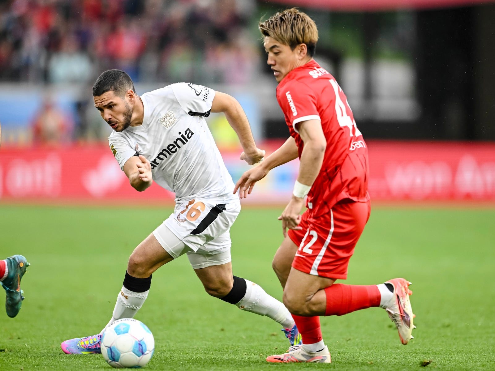Leverkusen's Emiliano Buendia, left, vies for the ball with Freiburg's Ritsu Doan, during the German Bundesliga soccer match between, SC Freiburg and Bayer Leverkusen, at Europa-Park Stadium, in Freiburg im Breisgau, Germany, Sunday, May 4, 2025. (Harry Langer/dpa via AP)