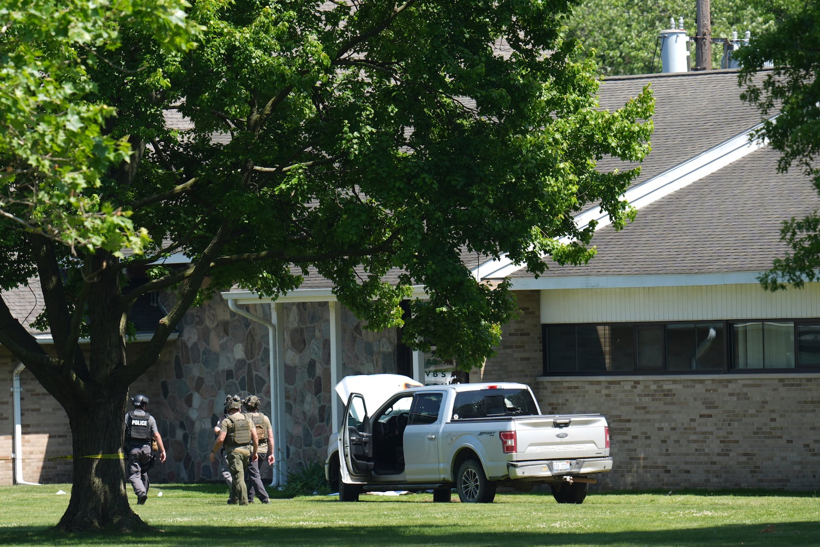 Police walk by an idle vehicle near CrossPointe Community Church in Wayne, Mich., Sunday, June 23, 2025. (AP Photo/Paul Sancya)