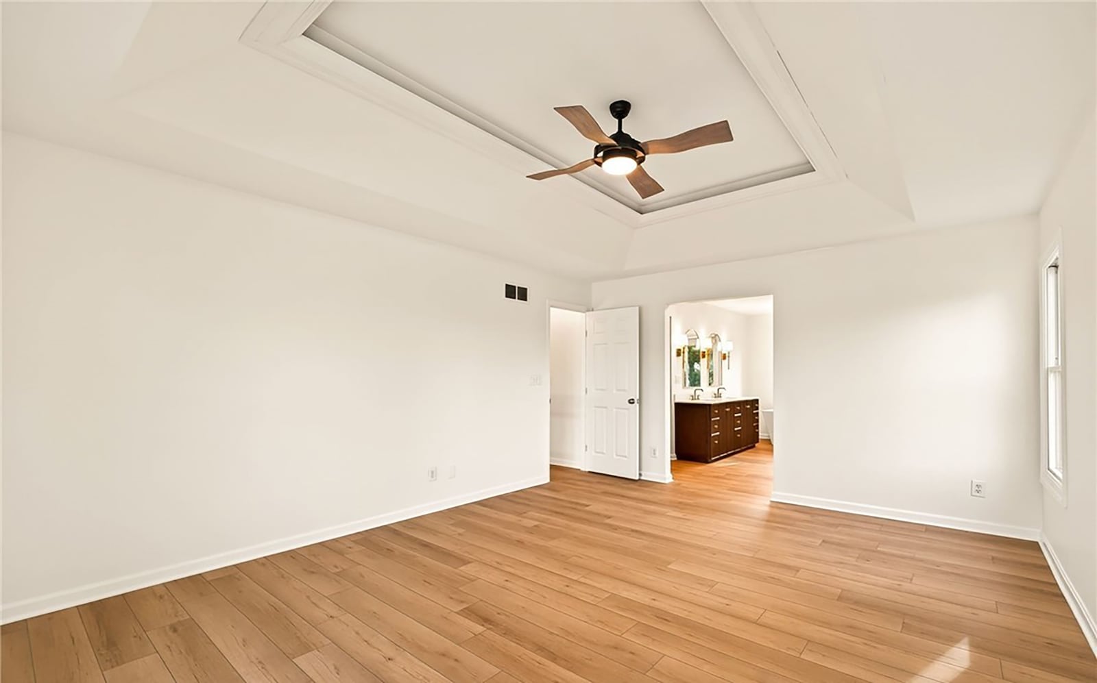 The second floor primary suite has a tray ceiling, ceiling fan, hardwood floors, and an ensuite bathroom with freestanding bathtub and walk in shower. CONTRIBUTED