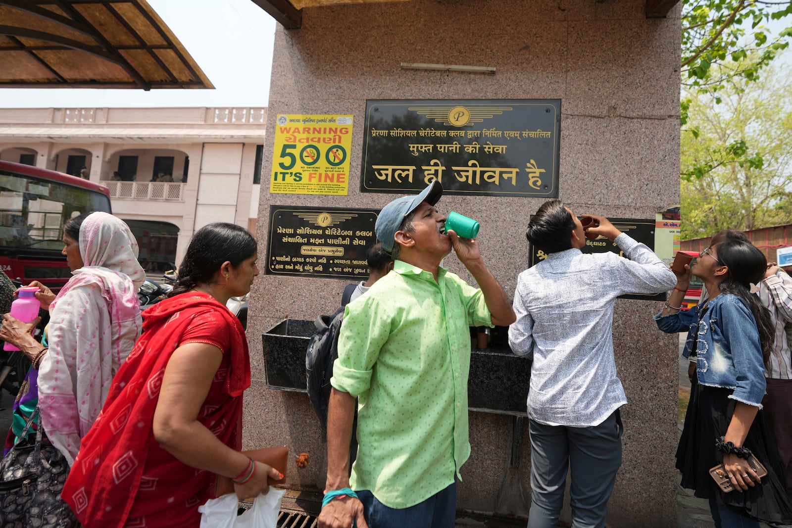 People drink water at a distribution center at a bus stop in Ahmedabad, India, Wednesday, April 2, 2025. (AP Photo/Ajit Solanki)