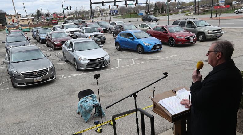 The Reverend John Pollock, pastor of St. John’s Lutheran Church, presides over the Good Friday service in the parking lot of the church. Parishioners lined their cars up and stayed inside them with their window open to hear Pollock’s sermon. The church will have a similar service on Easter Sunday. BILL LACKEY/STAFF