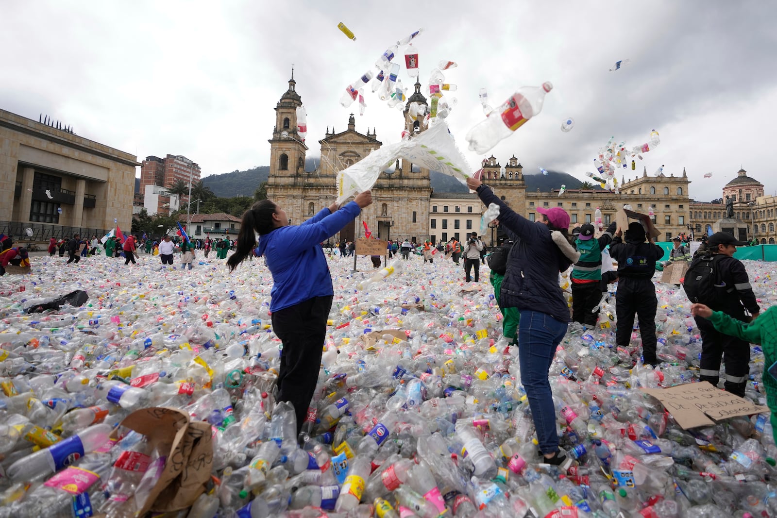 Recyclers throw plastic bottles into the air at Plaza Bolivar in Bogota, Colombia, as they protest what they consider to be too low a price paid to them by companies that buy recycled materials, Tuesday, June 24, 2025. (AP Photo/Fernando Vergara)