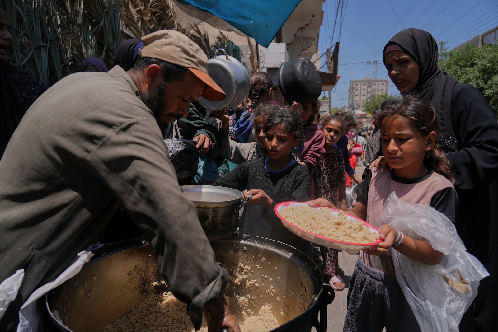 Palestinian children get food at a food distribution kitchen in Deir al-Balah, Gaza Strip, Friday, May 30, 2025. (AP Photo/Abdel Kareem Hana)