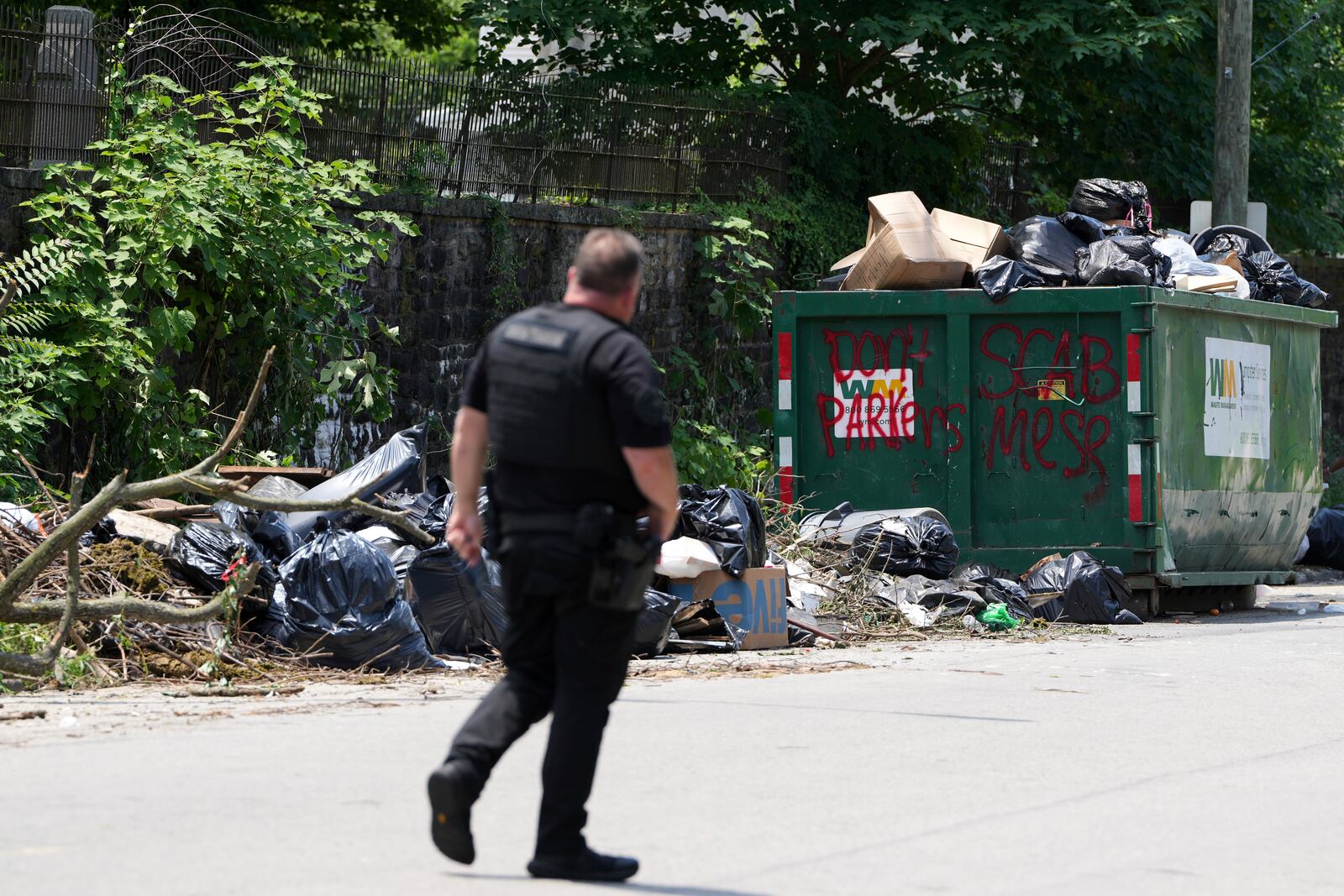 A police officer walks past a garbage collection site, Wednesday, July 9, 2025, in Philadelphia. (AP Photo/Matt Slocum)