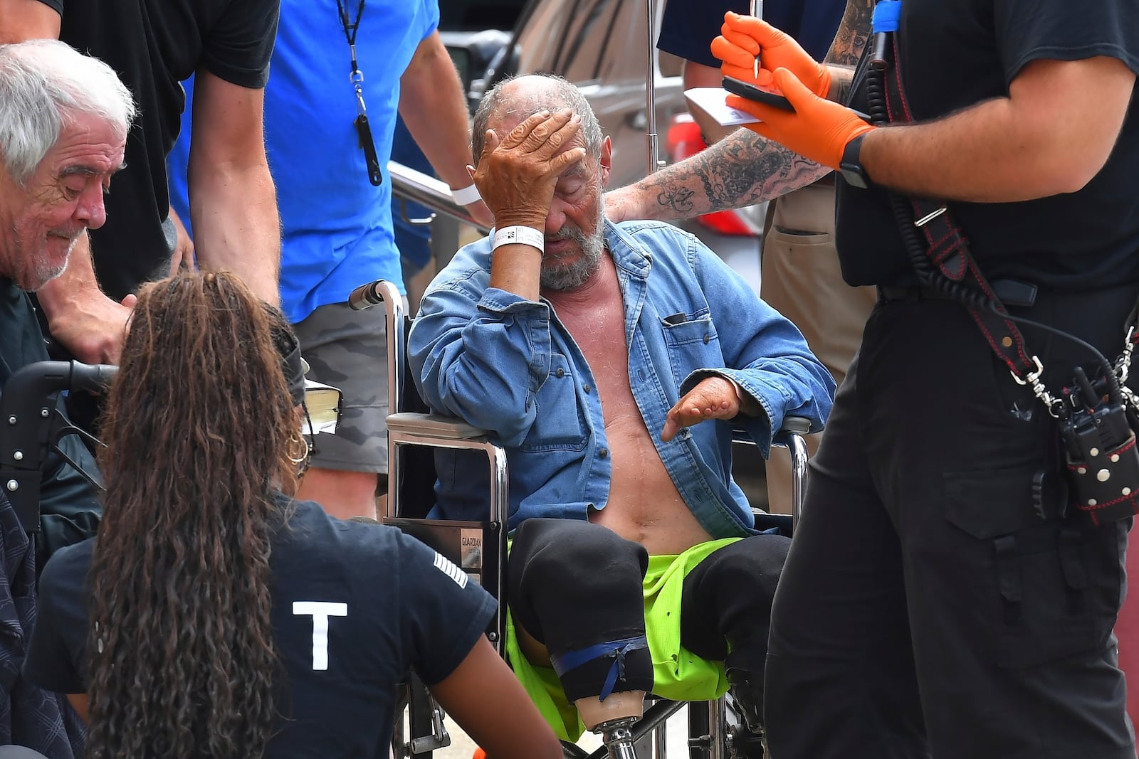 Michael Pimentel, center, a resident at the Gabriel House assisted living facility, in Fall River, Mass., receives assistance from an emergency medical worker, right, outside a temporary shelter, Monday, July 14, 2025, in Fall River, following a fire that started late Sunday. (AP Photo/Steven Senne)