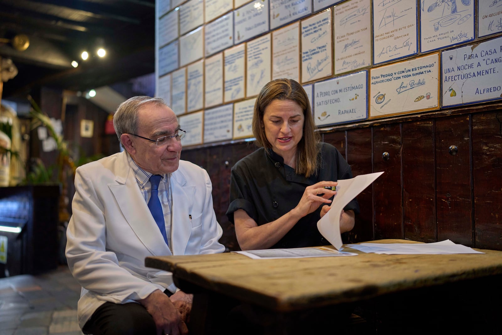 Irene Guinales, right, and Pedro Guinales del Valle, owners and managers of Casa Pedro restaurant, review documents regarding the restaurant's opening date in Madrid, Spain, on May 16, 2025. (AP Photo/Manu Fernandez)
