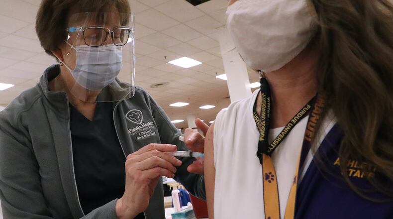 Ellen Dudney gives Lynne Willis, from Emmanuel Christian Academy, her COVID-19 vaccine injection last month. BILL LACKEY/STAFF