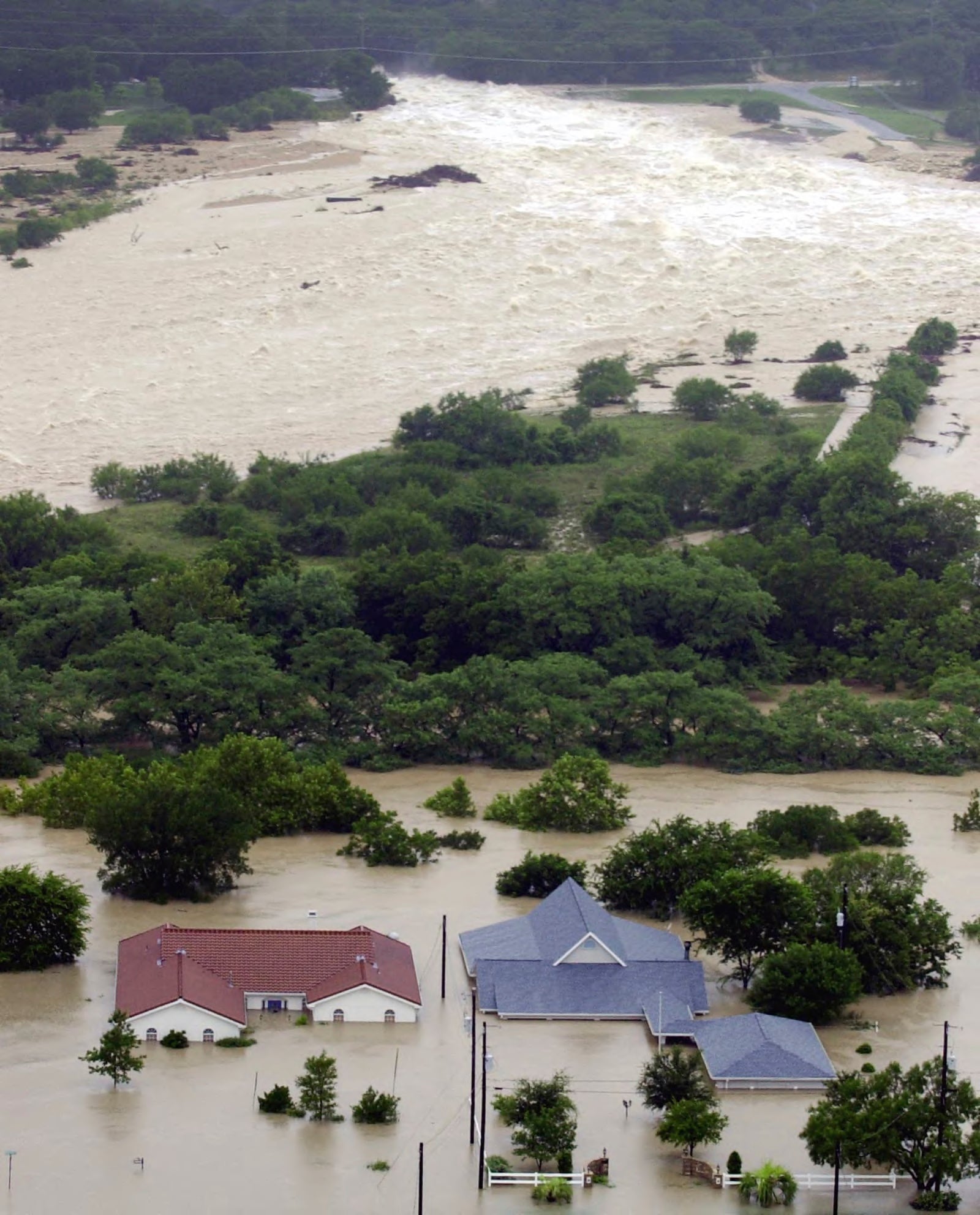FILE - Water flows from the Canyon Lake spillway near New Braunfels, Texas, Friday, July 5, 2002, adding to the flood waters along the Guadalupe River. (AP Photo/Eric Gay, File)