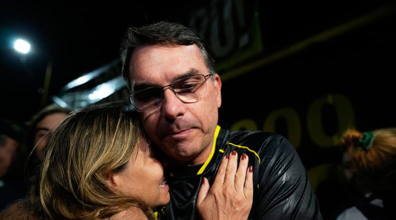 Flavio Bolsonaro, son of ex-President Jair Bolsonaro, hugs a supporter during a vigil outside the former president's residence in Brasília, Brazil, Saturday, Nov. 22, 2025, after his father's arrest earlier in the day, carried out days before he was set to start serving his 27-year sentence for leading a coup attempt. (AP Photo/Eraldo Peres)
