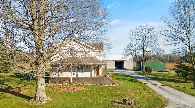 A gravel driveway leads to the two barns on the property and the front of the home, which has a wraparound porch and wooden steps and railings. Contributed photos