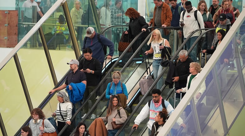 Travellers head tdown an escalator after clearing through a security checkpoint in Denver International Airport Friday, Nov. 7, 2025, in Denver. (AP Photo/David Zalubowski)