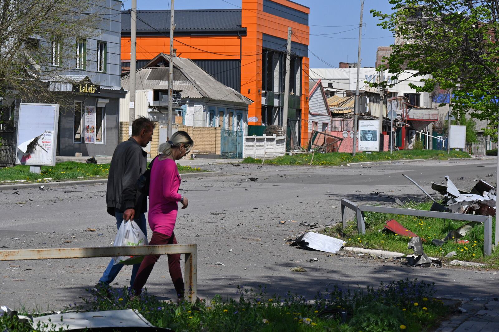 Local residents walk past damaged buildings in central Pokrovsk, the site of the heaviest battles with the Russian troops in the Donetsk region, Ukraine, Wednesday, April 23, 2025. (AP Photo/Michael Shtekel)