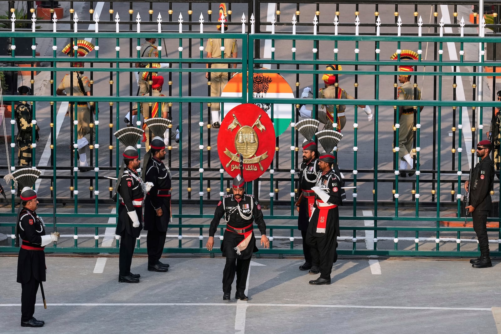 Pakistan's Rangers soldiers, in black, and Indian Border Security Forces soldiers, behind the gate, parade during a daily closing ceremony at the Wagah, a joint post on the Pakistan and India border, near Lahore, Pakistan, Monday, May 5, 2025. (AP Photo/K.M. Chaudary)