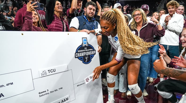 FILE - Texas A&M middle blocker Morgan Perkins, center, places the Texas A&M logo on an NCAA bracket after winning the NCAA Division I volleyball playoff game against TCU, Dec. 6, 2025, in College Station, Texas. (Aaron E. Martinez/Austin American-Statesman via AP, File)