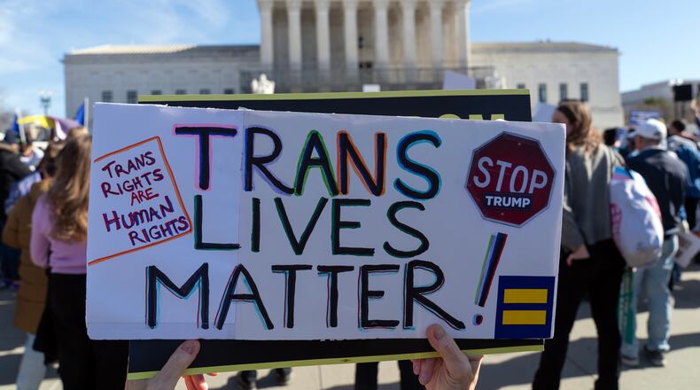 Protesters gather outside the Supreme Court as it hears arguments over state laws barring transgender girls and women from playing on school athletic teams, Tuesday, Jan. 13, 2026, in Washington. (AP Photo/Jose Luis Magana)