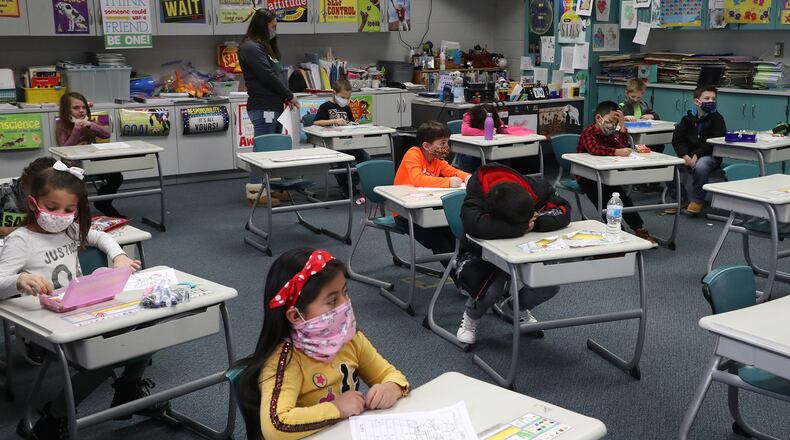 INITIAL CUTLINE: With masks and desks spaced apart, students at Simon Kenton Elementary work on classwork Friday, Feb. 19, 2021.