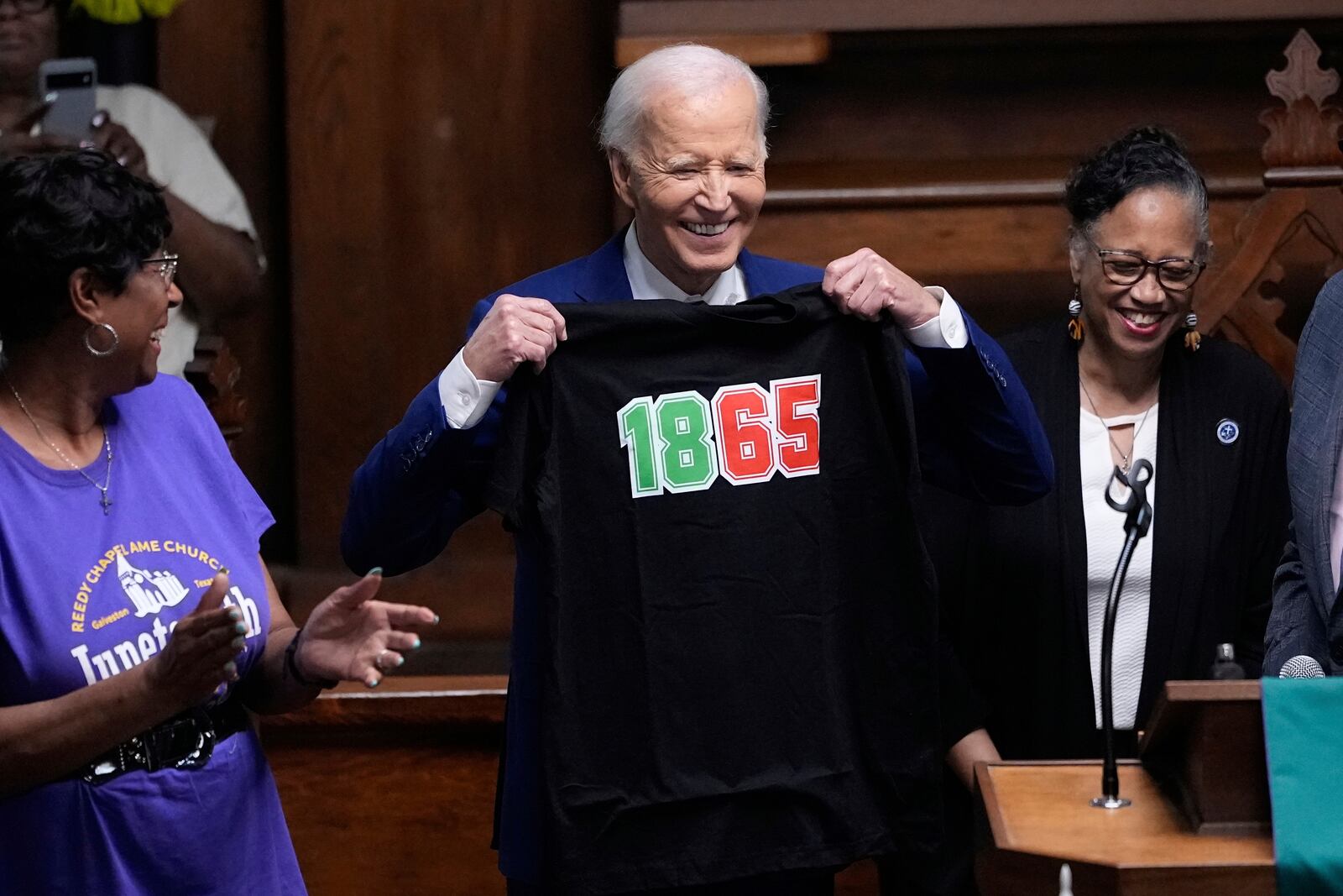 Former President Joe Biden holds up a tee shirt during a Juneteenth event at the Reedy Chapel AME Church, Thursday, June 19, 2025, in Galveston, Texas. (AP Photo/David J. Phillip)