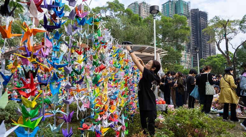 People hang paper cranes near the site of the fire at Wang Fuk Court, a residential estate in the Tai Po district of Hong Kong's New Territories on Wednesday, Dec 3, 2025. (AP Photo/Chan Long Hei)