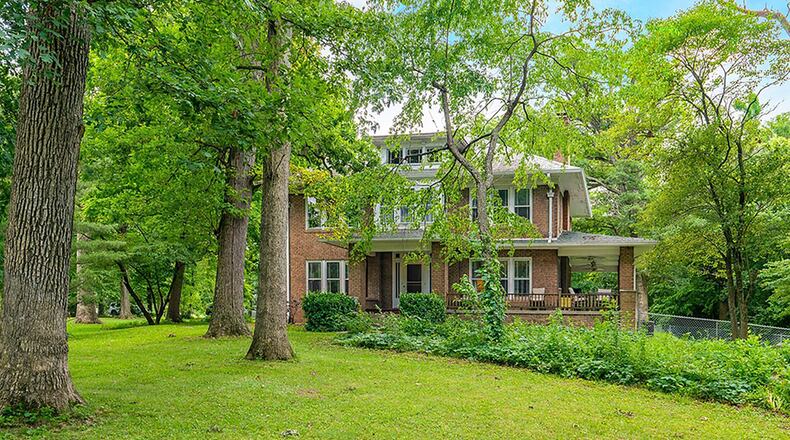 Originally built in 1918, the brick 2-story sits among mature trees on a 2.6-acre lot. The home offers about 2,660 sq. ft. of living space with 4 bedrooms and a second-floor sunroom. A covered porch wraps around the front and side of the home. CONTRIBUTED PHOTO