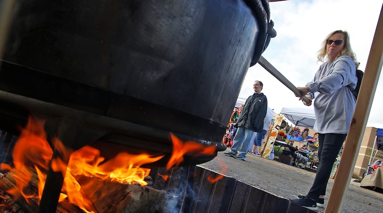 Cindy Leist takes a turn stirring one of the cauldrons of apple butter cooking over an open fire at the Enon Apple Butter Festival Saturday, Oct. 14, 2023. BILL LACKEY/STAFF