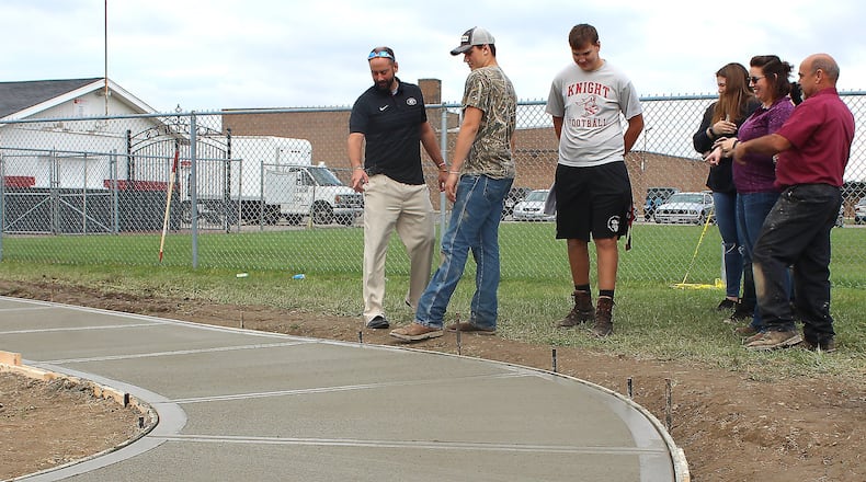 Students and teachers in the Greenon High School FFA club helped install a new cement side walk near the high school football field. JEFF GUERINI/STAFF