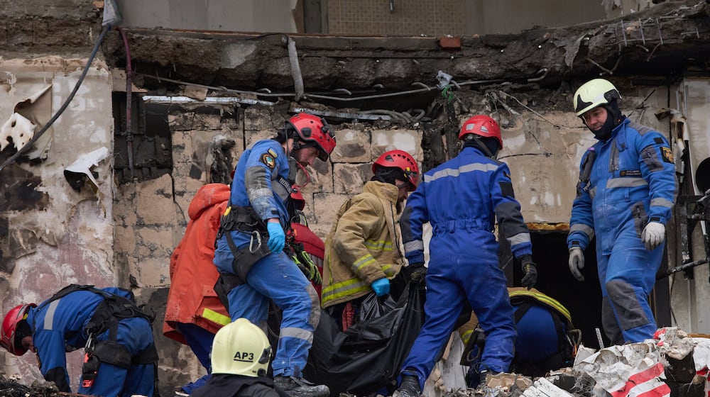Rescuers carry the body of a victim after Russian drone hit a multi-storey apartment building during a massive missile and drone attack in Kyiv, Ukraine, Saturday, Dec. 27, 2025. (AP Photo/Efrem Lukatsky)