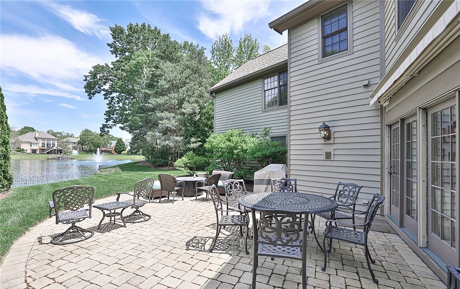 The rear of the home has a paver patio and retractable awning that overlooks a lake.
