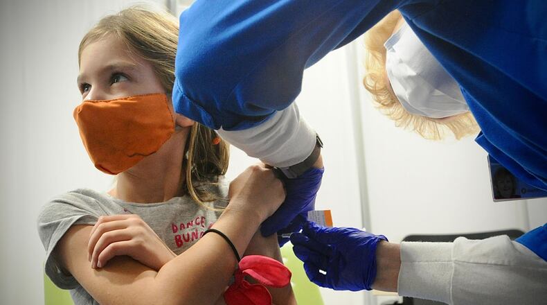 Thea Schicel, age 6, looks at her mother while receiving her COVID-19 vaccine at Dayton Children's Monday, Nov. 8, 2021. MARSHALL GORBY\STAFF
