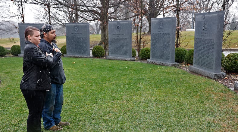 Taps plays from a cell phone in Kiana Sanders’ pocket as she and Al Hernandez stand quietly in rain at the War Wall at Ferncliff Cemetery in Springfield on Friday, Nov. 11, 2022, to pay their respects to the fallen soldiers from America’s wars. The couple went to the cemetery for the Veterans Day service but found it was canceled because of the weather, so they decided to have a small service of their own. “The veterans and fallen soldiers went through a lot more than a little rain,” Hernandez said. BILL LACKEY/STAFF