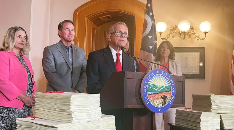 Ohio Gov. Mike DeWine, surrounded by the over 6,000 pages making up Ohio's $86 million state budget, addresses reporters at a press conference, Wednesday, July 5, 2023, at the Ohio Statehouse in Columbus, Ohio. (AP Photo/Samantha Hendrickson)