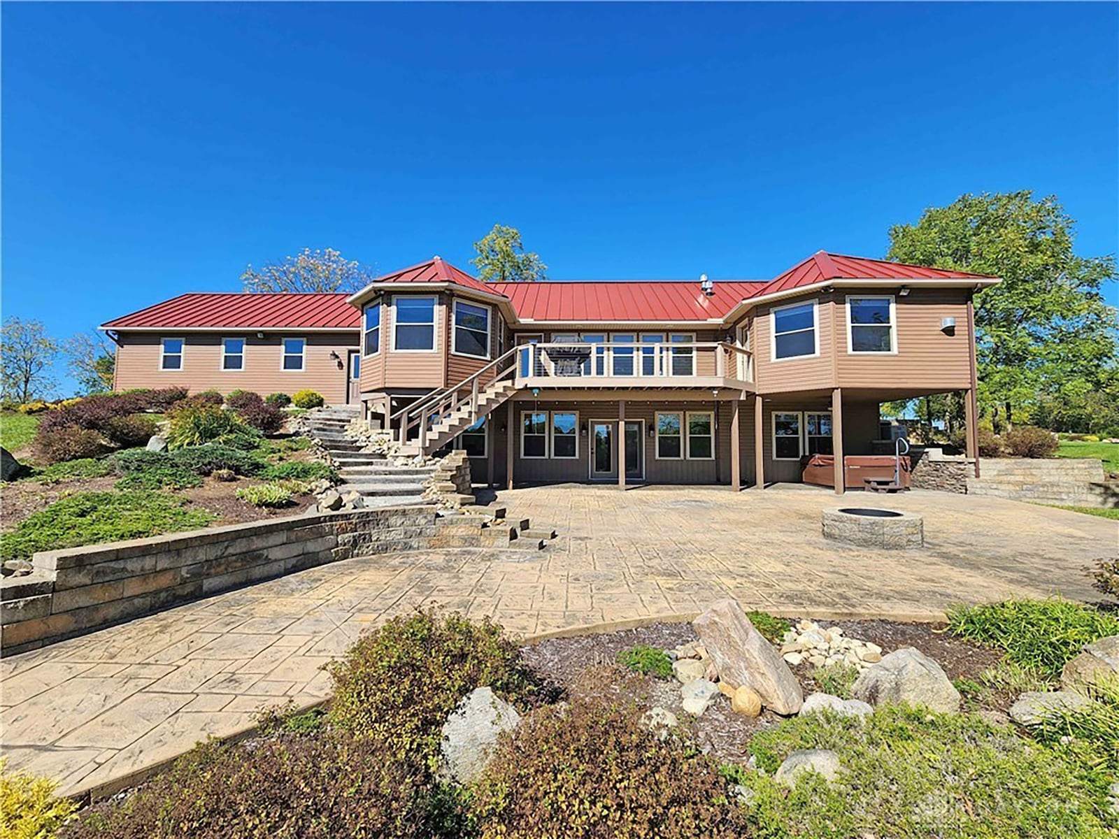 The rear of the home features a raised deck that steps down to a large stamped concrete patio with firepit.