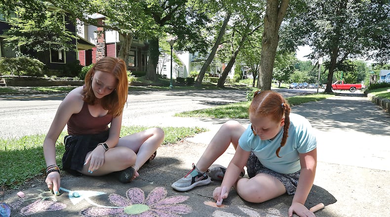 Mary Cunningham, left, and her sister, Helen, brighten up the sidewalk along South Fountain Avenue with chalk drawings of flowers Wednesday, July 13, 2022. BILL LACKEY/STAFF