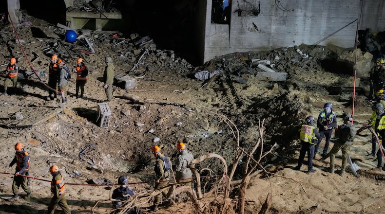 Israeli security forces and rescue teams inspect the crater left by an Iranian missile in Arad, southern Israel, Sunday, March 22, 2026. (AP Photo/Ohad Zwigenberg)
