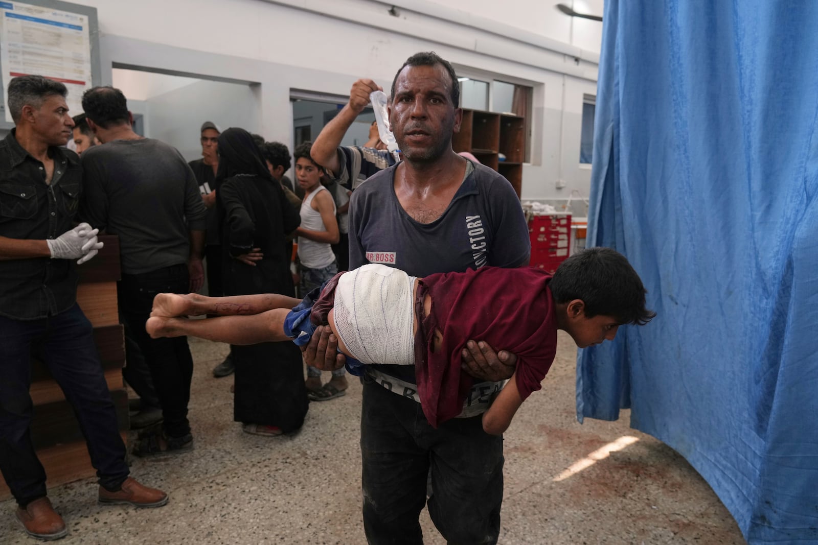 A man carries a child, who was wounded in an Israeli strike, after being treated in the Shifa Hospital, Gaza City, Monday, June 30, 2025. (AP Photo/Jehad Alshrafi)