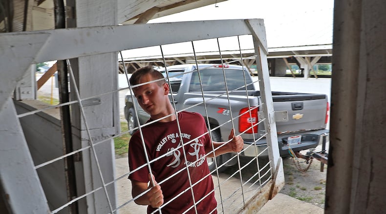 Trent Green carries part of a cow pen into one of the cattle barns at the Clark County Fairgrounds for the stall in the Young’s Dairy section Thursday. BILL LACKEY/STAFF
