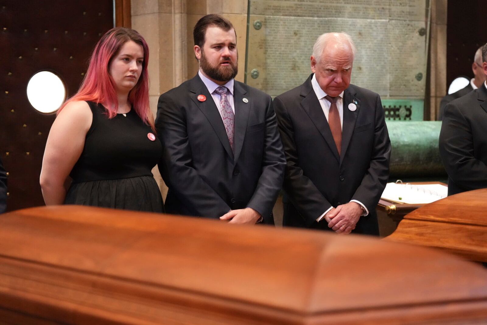 Alina Bachman, Colin Hortman, and Gov. Tim Walz stand behind the caskets of Melissa and Mark Hortman during funeral services for Mark and Melissa Hortman at the Basilica of St. Mary in Minneapolis, Minn., on Saturday, June 28, 2025. (Alex Kormann/Star Tribune via AP, Pool)