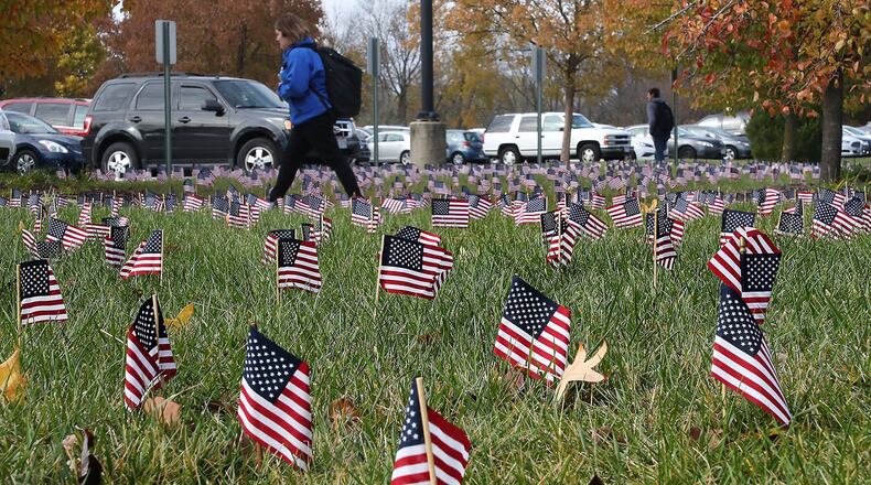 Students at Clark State Community College walk past the 2,000 American flags decorating the lawns on campus Monday. The flags kick off a week of activities to honor veterans for Veteran’s Day which is Sunday. BILL LACKEY/STAFF