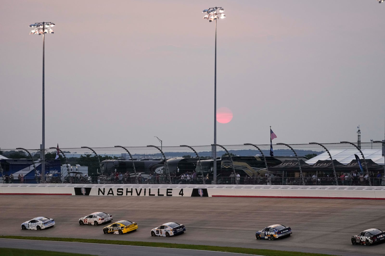 Drivers speed through turn four as the sun sets during a NASCAR Cup Series auto race Sunday, June 1, 2025, in Lebanon, Tenn. (AP Photo/George Walker IV)