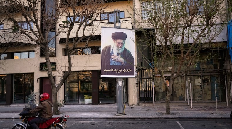 A motorcycle drives past a picture of the late Iranian Supreme Leader Ayatollah Ali Khamenei along an empty street in Tehran, Iran, Sunday, March 1, 2026, following the confirmed death of Khamenei in U.S. and Israeli strikes. (AP Photo/Vahid Salemi)