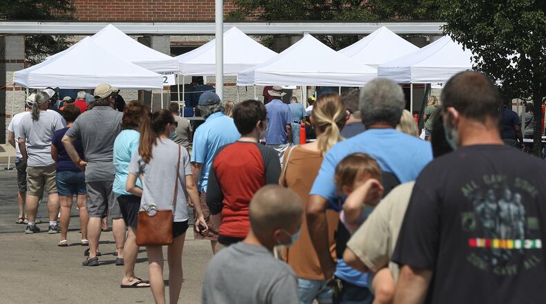 People wait in line at the Clark County Combined Health District's free COVID-19 testing clinic at Perrin Woods Elementary School in Springfield Wednesday. BILL LACKEY/STAFF