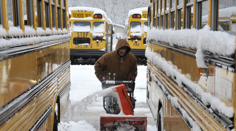 In this file photo from years ago, Tom Jenkins, a bus driver for Springfield City Schools, used a snow blower to clear a path between the school district’s buses. Schools in the area were closed Tuesday after snowy weather and freezing temperatures. FILE/Bill Lackey/Staff