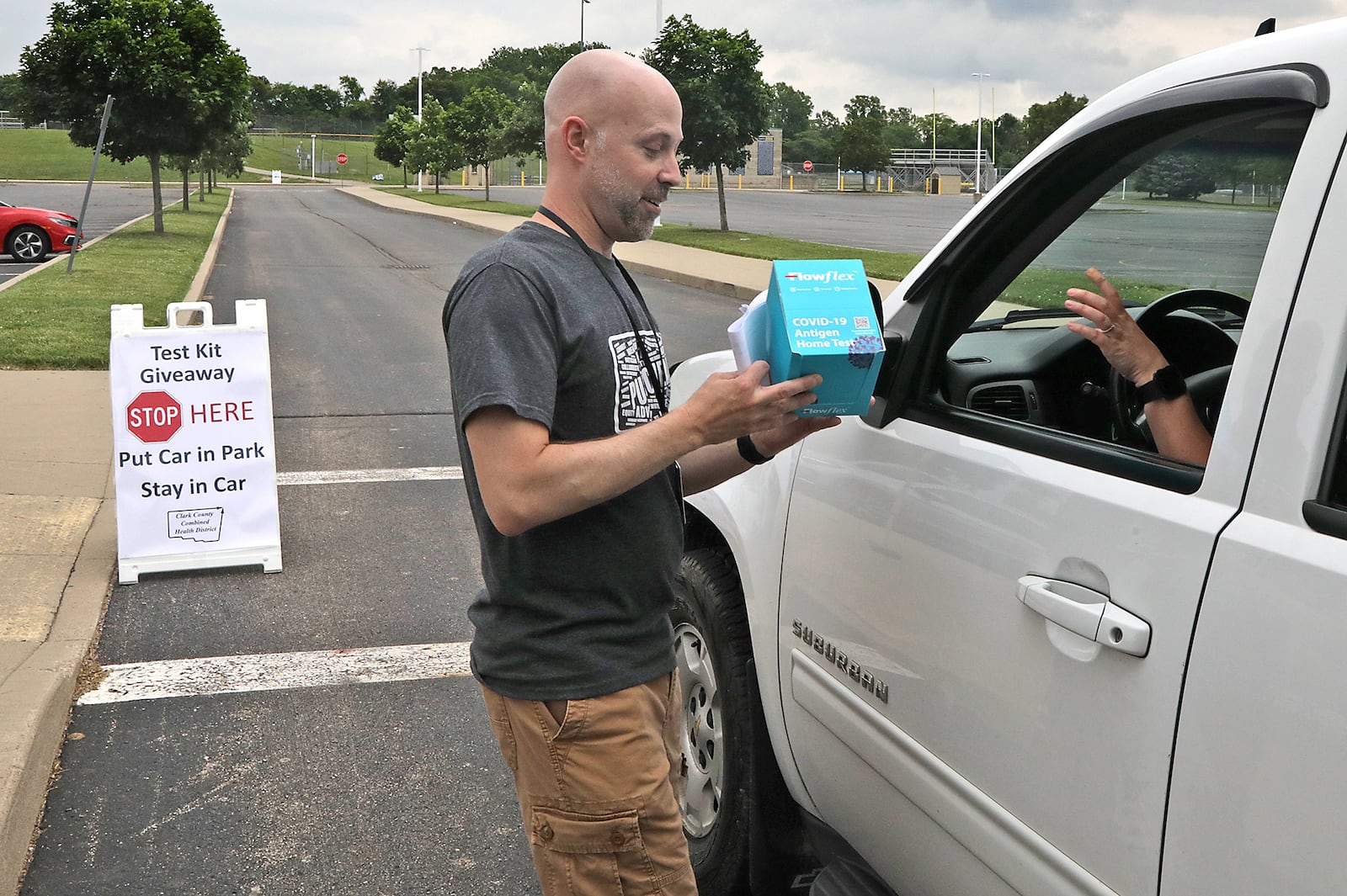 Chris Cook, from the Clark County Combined Health District, passes out COVID-19 home test kits in a drive-thru Tuesday, June 7, 2022 set up in the parking lot at Springfield High School. BILL LACKEY/STAFF