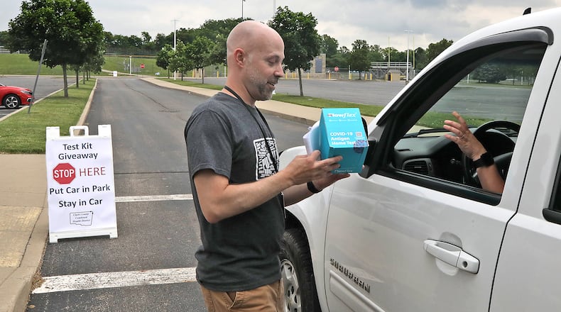 Chris Cook, from the Clark County Combined Health District, passes out COVID-19 home test kits in a drive-thru Tuesday, June 7, 2022 set up in the parking lot at Springfield High School. BILL LACKEY/STAFF