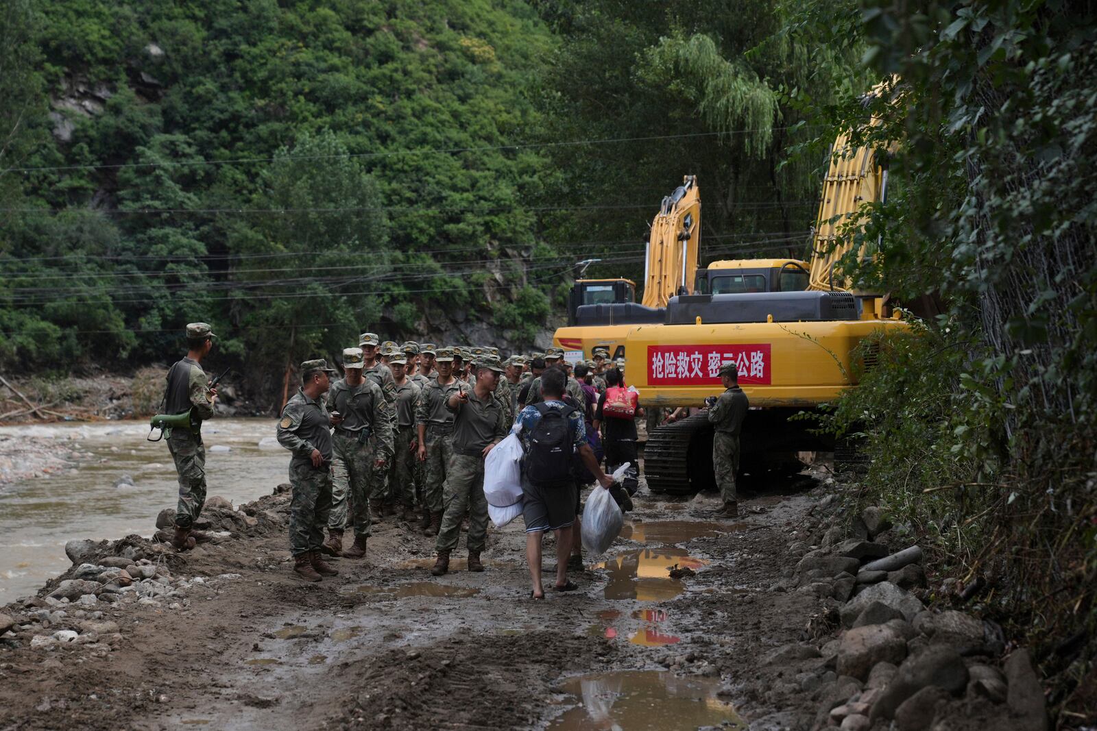 Soldiers talk to villagers on a road damaged by flood as they evacuate from the Langjiayu village after heavy rains in Miyun district on the outskirts of Beijing, Tuesday, July 29, 2025. (AP Photo/Andy Wong)