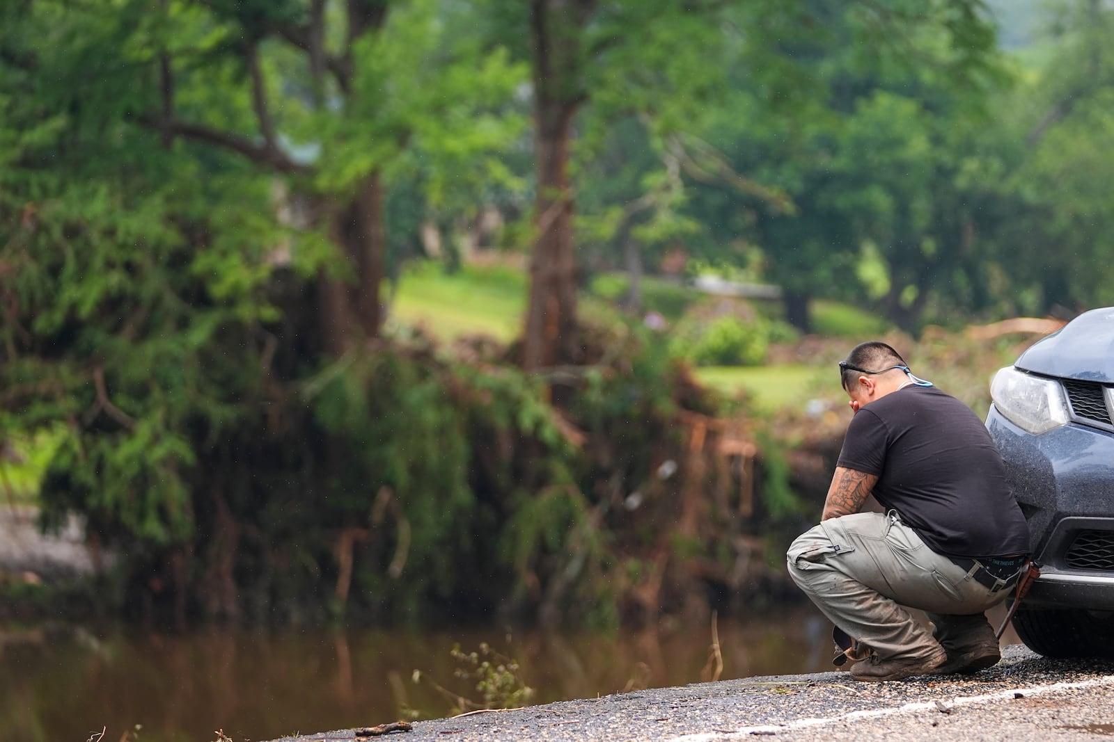 Avi Santos, 23, of San Antonio, Texas, reacts while stopping on the road alongside at Camp Mystic along the banks of the Guadalupe River after a flash flood swept through the area Sunday, July 6, 2025, in Hunt, Texas. (AP Photo/Julio Cortez)